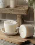 Two white candles on a wooden surface with a blurred background
